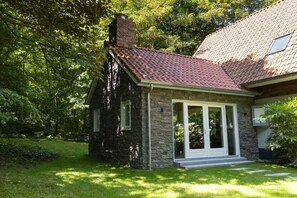 A stone house with a red-tiled roof, a chimney, and a glass door entrance. - Holiday home with 2 bedrooms (Groot-Valkenisse)