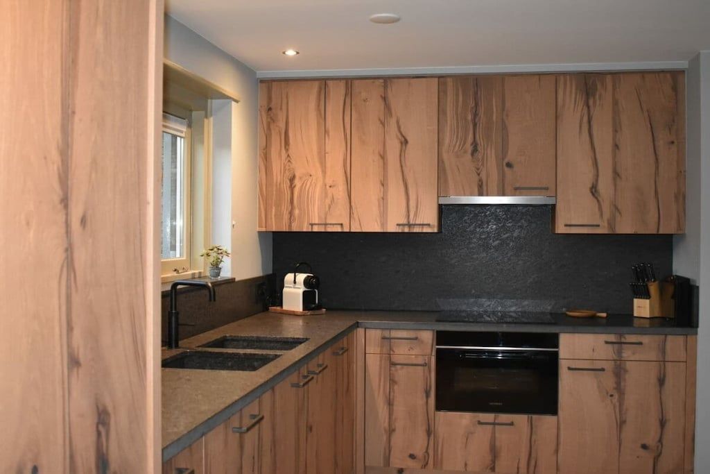A kitchen with wooden cabinets, a black countertop, and a built-in oven.