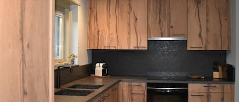 A kitchen with wooden cabinets, a black countertop, and a built-in oven.