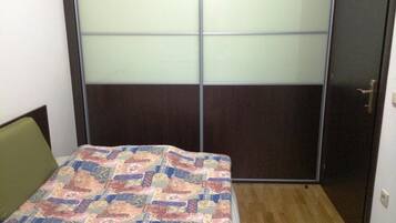 A bedroom with a bed, a wooden floor, a wardrobe with frosted glass panels, and a door.