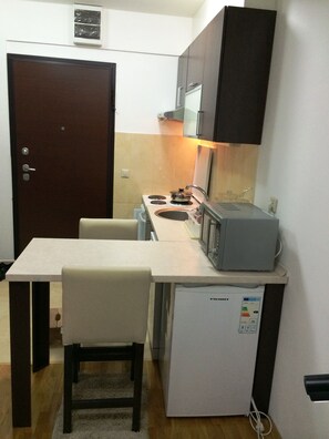 Cocina compacta con refrigerador, microondas, estufa y pileta.