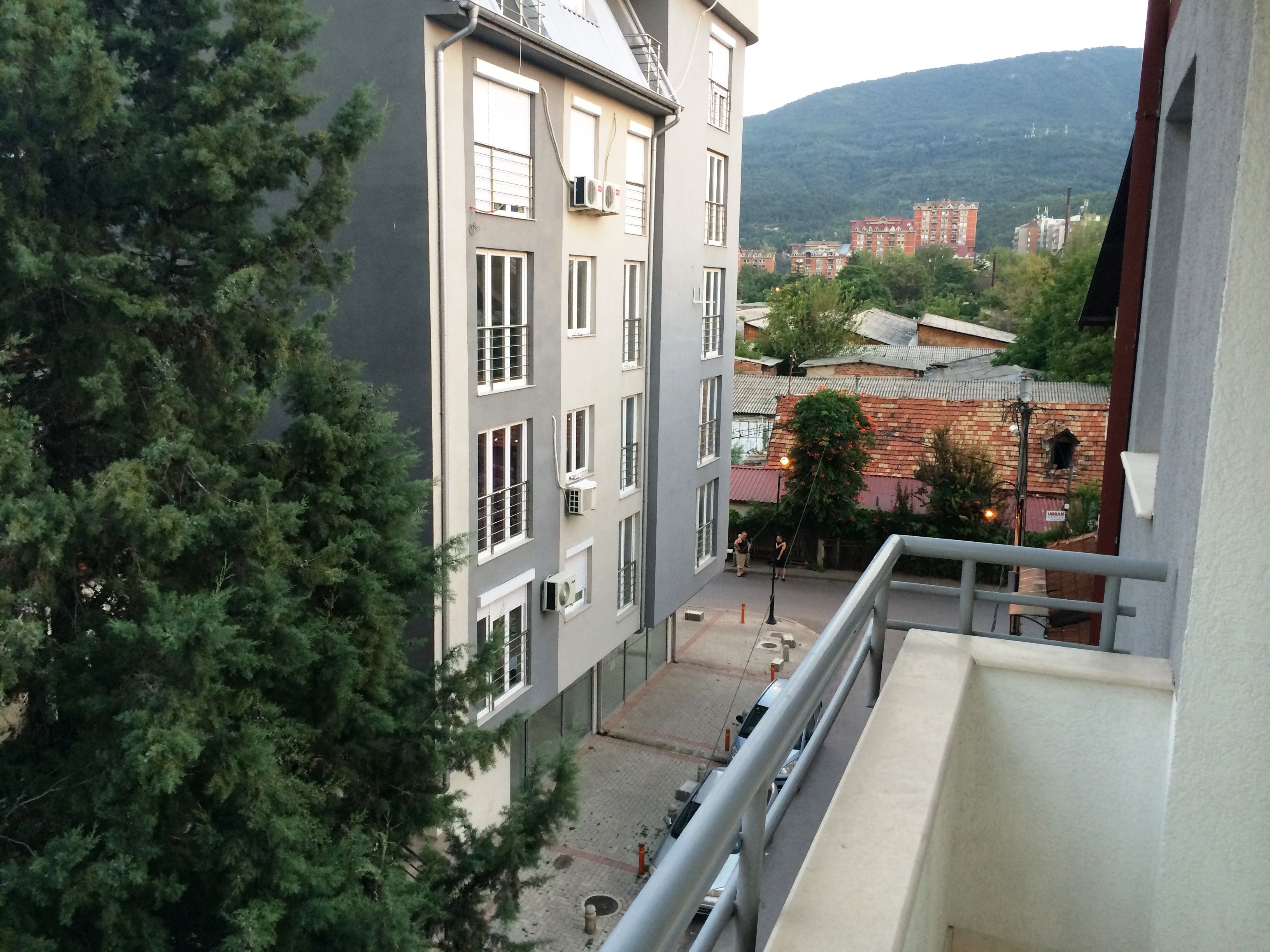 A multi-story building with balconies, a courtyard, and a view of a mountainous landscape.