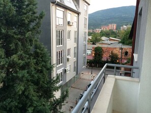 Un edificio de varios pisos con balcones, un patio interior y vistas a un paisaje montañoso.