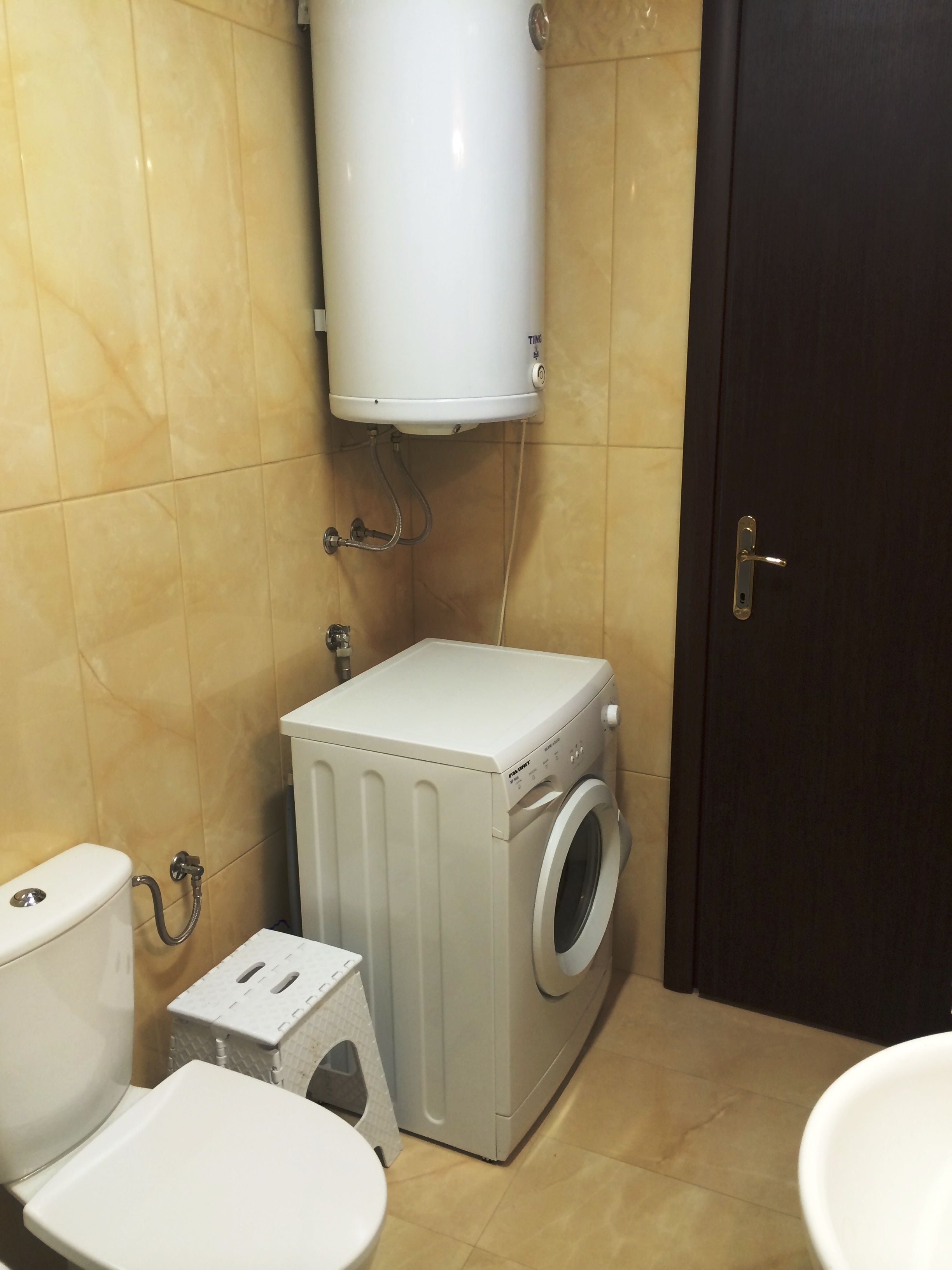 Un baño pequeño con inodoro, lavadora y calentador de agua.
