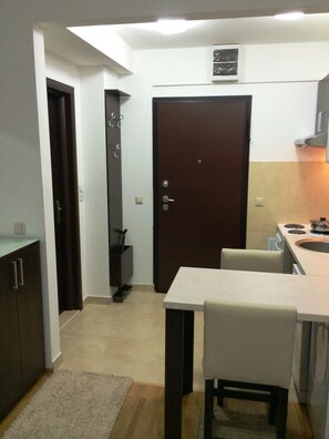 A compact kitchen with a dining area, a dark wooden door, and a small window. - Fortuna Fortis Apartments - Suite 7 (Skopje)