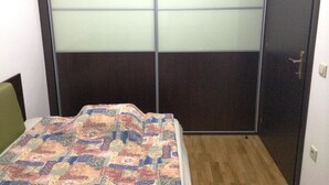 Una camera da letto con un letto, un armadio con vetri satinati e un pavimento in legno.