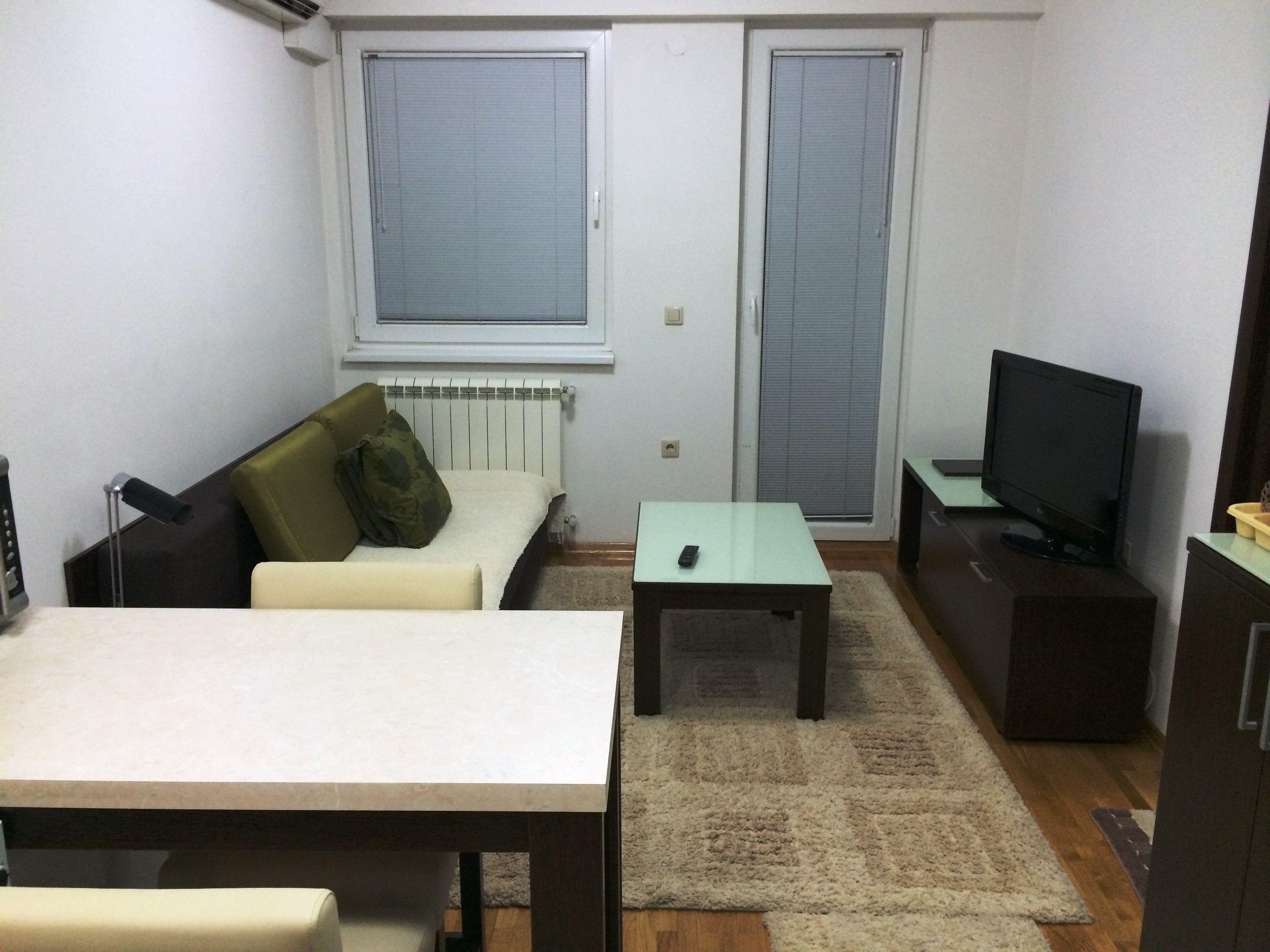 Un petit salon avec un canapé, une table, un téléviseur et un radiateur.