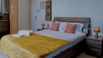 A hotel room with a bed, two bedside tables, a wooden headboard, and a wall-mounted mirror.