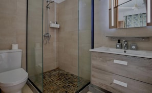 A modern bathroom with a glass-enclosed shower, a white toilet, and a wooden vanity with a mirror.