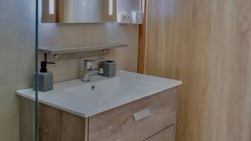 Une salle de bain avec un lavabo blanc, un miroir et un meuble-lavabo en bois.