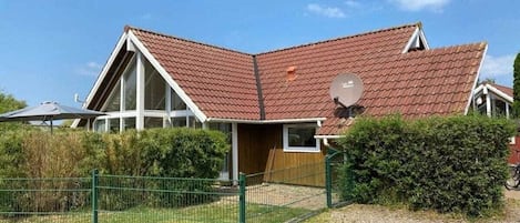 Talo, jossa on kalteva katto, satelliittiantenni ja aidattu piha.