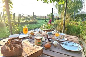A picnic setup with food, drinks, and a rustic table in a garden.