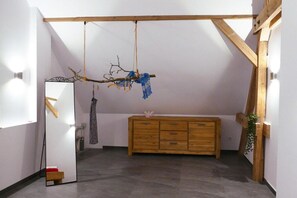 Ein Zimmer mit einem Holzkabinett, einem hängenden Ast als Dekoration und einem Spiegel.