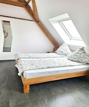 A loft bedroom with a sloped ceiling, a bed with patterned bedding, and a skylight.