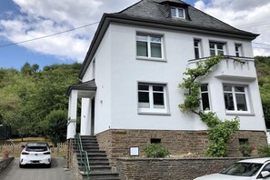 A two-story house with a stone foundation and white exterior walls. - Villa on Bleidenberg (Oberfell)