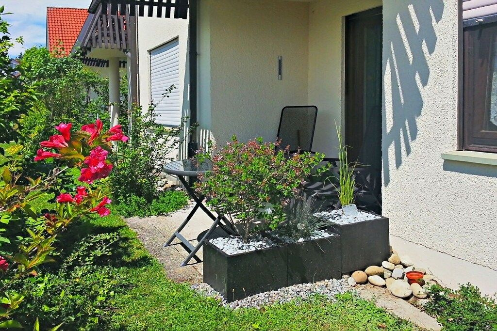 Ein Garten mit einer Terrasse, einem Tisch, einem Stuhl und einem Blumentopf.