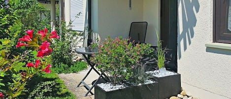 Ein Garten mit einer Terrasse, einem Tisch, einem Stuhl und einem Blumentopf.