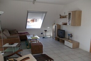 Ein modernes Wohnzimmer mit einer Couch, einem Couchtisch, einem Fernseher und einem Bücherregal.