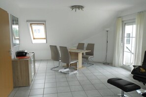 A modern, well-lit room with a dining table, chairs, a bench, a desk with a computer, and a large window. - Holiday apartment with 2 bedrooms (Seelbach)