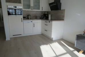 Une cuisine moderne avec des meubles blancs, un four encastré et un four à micro-ondes.
