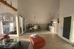 Ein modernes Interieur mit einem Esstisch aus Glas, einem roten Sofa und einer Küchenzeile.