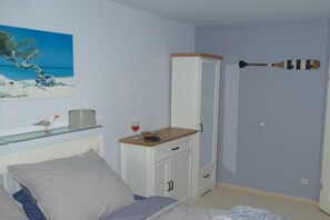 A bedroom with a bed, a nightstand, a cabinet, a painting, and a wall-mounted paddle. - Holiday apartment in Zingst with balcony (Zingst)