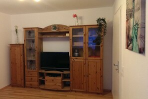 Eine Holz-Unterhaltungsanlage mit Fernseher, Glastüren und einer Tür zu einem anderen Raum.