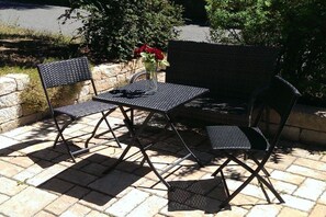 An outdoor seating area with a metal table and chairs, a vase with red flowers, and a brick wall in the background. - Holiday apartment on the Rhine and Moselle (Koblenz)