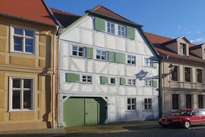 Een gebouw met twee verdiepingen, een garage deur en een rode auto geparkeerd ervoor.