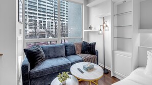 A modern living room with a sofa, a coffee table, and a view of a high-rise building. - StayToronto - Toronto Central Studio - DT (Toronto)