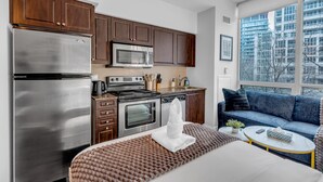A modern kitchen with stainless steel appliances, wooden cabinets, and a large window offering a city view. - StayToronto - Toronto Central Studio - DT (Toronto)