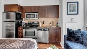 A modern kitchen with stainless steel appliances, wooden cabinets, and a built-in oven. - StayToronto - Toronto Central Studio - DT (Toronto)