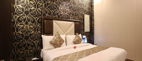 A hotel room with a large bed, a headboard, and a patterned wall.
