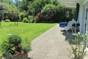 A patio area with a table and chairs, a swing set, and a well-maintained lawn. - Holiday apartment with 2 bedrooms (Uhldingen-Mühlhofen)