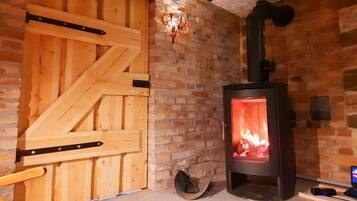 A room with a brick wall, a wooden door, and a wood-burning stove.