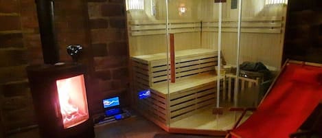 A sauna with a glass enclosure, a wooden bench, and a red chair.