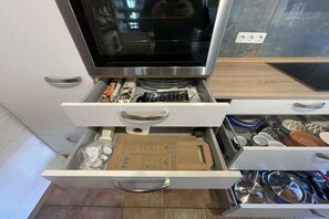 Eine Küche mit Mikrowelle, Kühlschrank und einer Schublade voller Küchenutensilien und Behälter.