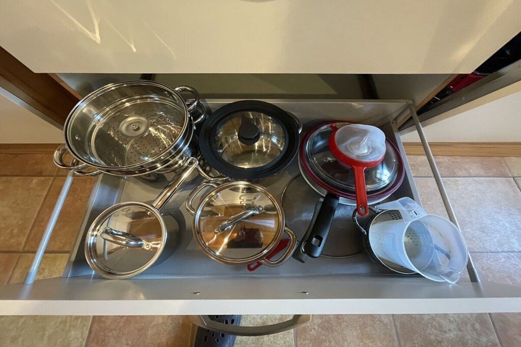 A kitchen drawer with various pots and pans.