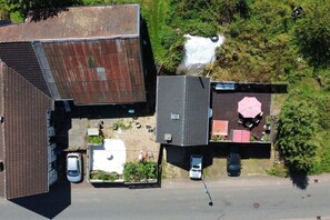 An aerial view of a residential area with houses, a road, and a small body of water. - Backhaus Oberbettingen (Oberbettingen)