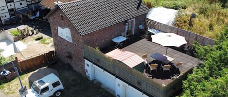 A residential property with a detached house, a garage, and a patio area with outdoor furniture.