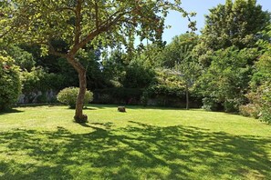 A well-maintained garden with a variety of trees and shrubs, a clear sky, and a grassy lawn. - Holiday apartment with 2 bedrooms (Ste. Honorine des Pertes)