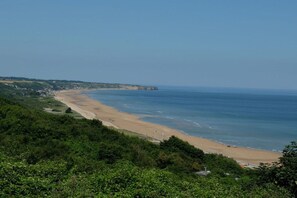 A coastal landscape with a beach, vegetation, and a clear sky. - Holiday apartment with 2 bedrooms (Ste. Honorine des Pertes)