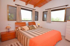 A bedroom with a bed, nightstands, a lamp, and curtains on windows.