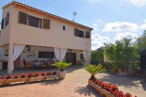 A two-story building with a covered patio area, outdoor seating, and potted plants. - Cabin in Muro with swimming pool (Muro)