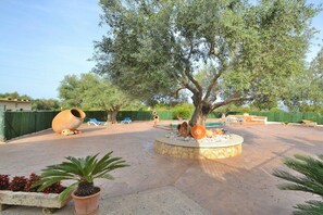An outdoor patio area with a large tree, outdoor seating, and decorative pottery.