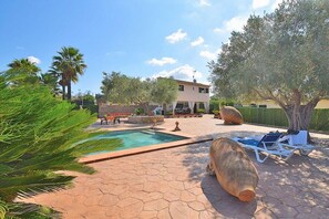 A pool area with a hexagonal tiled floor, lounge chairs, and a building in the background.