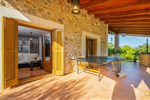 A room with a ping pong table, a stone wall, and a wooden ceiling.