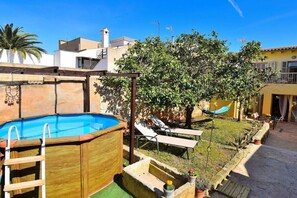 Ein Garten mit Swimmingpool, Hängematte und Baum.