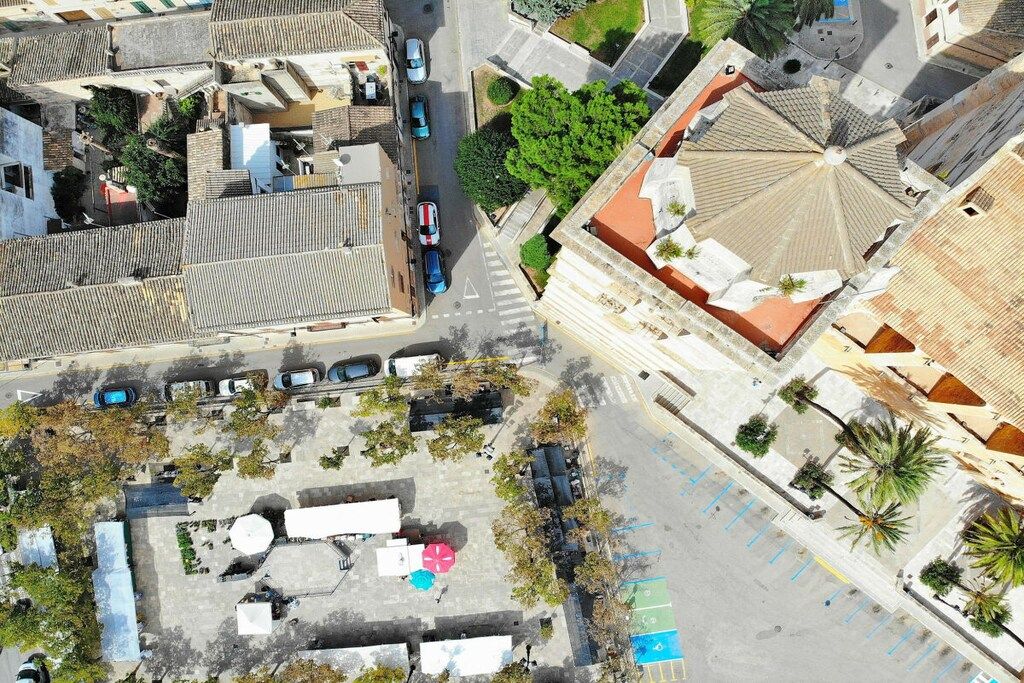 An aerial view of a cityscape with buildings, roads, and a parking area.