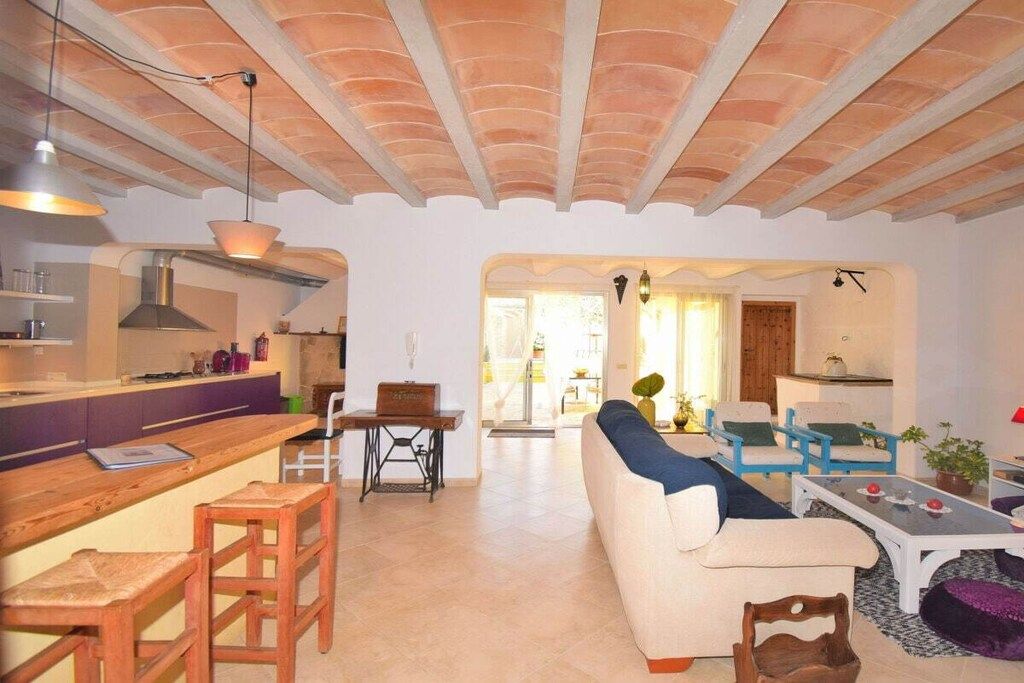 A spacious living area with a sofa, chairs, a dining table, and a kitchen area with a counter and stools.